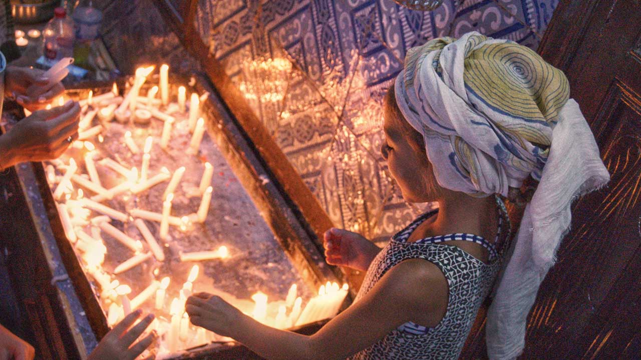 Jewish teen illuminating candles in El Ghriba Synagogue, Djerba